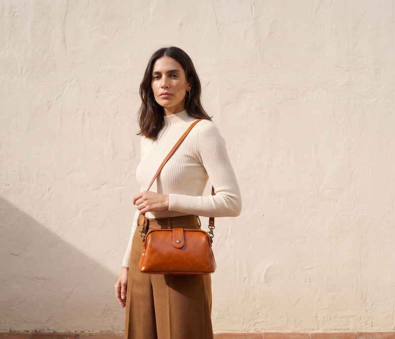 Bolso bandolera de piel conac sobre muro encalado